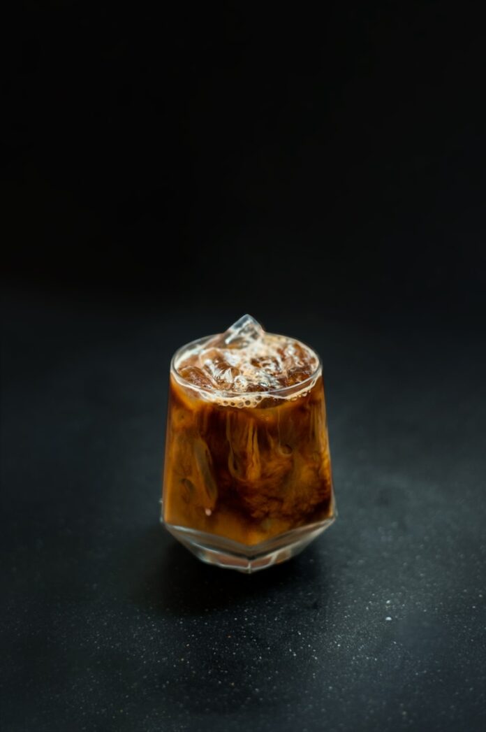 Photo by pariwat pannium a glass filled with liquid sitting on top of a table