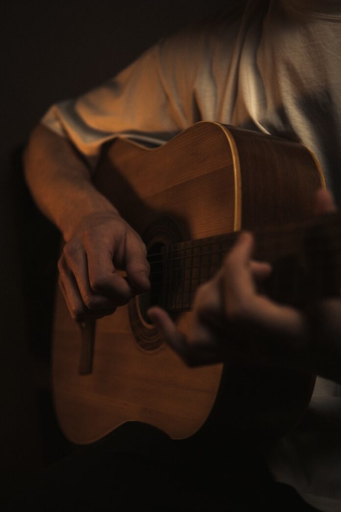 Photo by James Kovin a man playing a guitar in a dark room