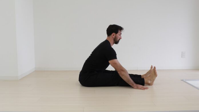 Photo by GMB Fitness a man sitting on the floor in a white room