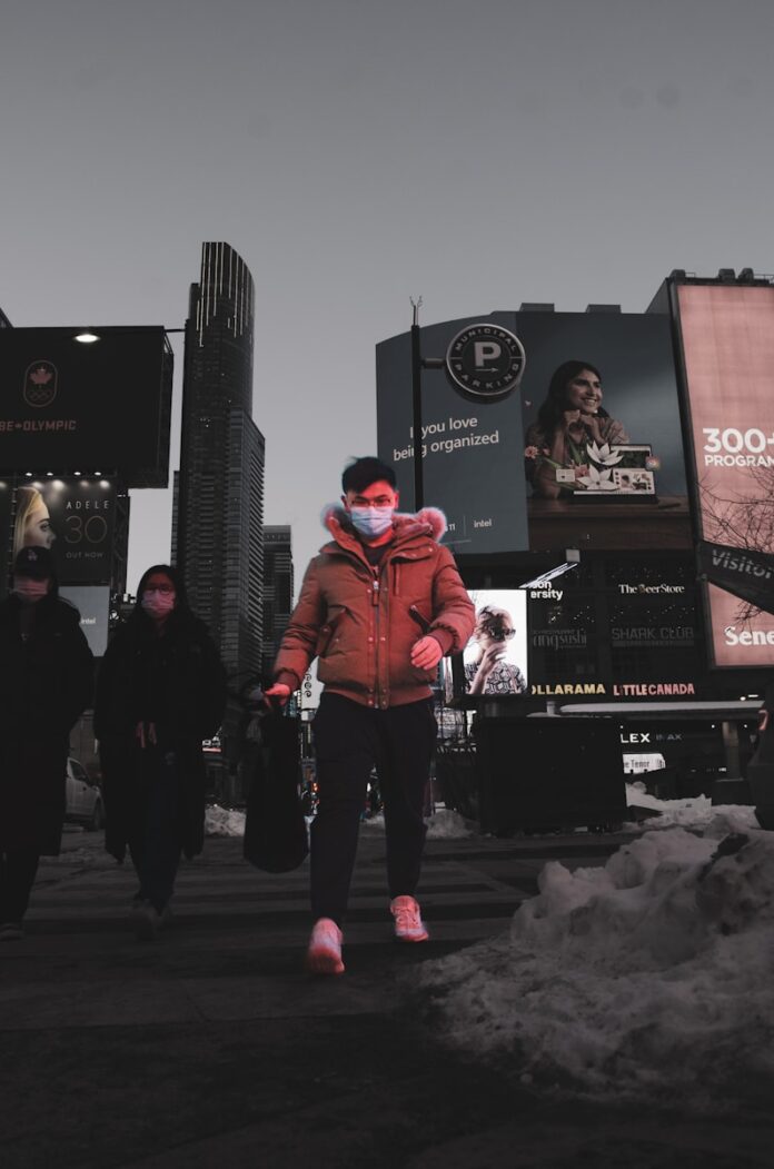 Photo by Hooman R. a woman wearing a face mask walking down a street