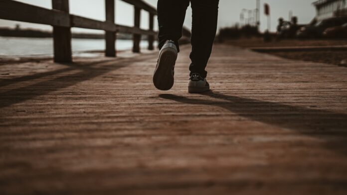 Photo by Chris Hardy person in black pants and black shoes standing on brown wooden dock during daytime
