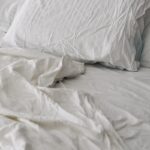 꿀잠을 위한 새로운 루틴, 수면 건강 트렌드와 실천법 A rumpled white duvet and pillows on a bed.